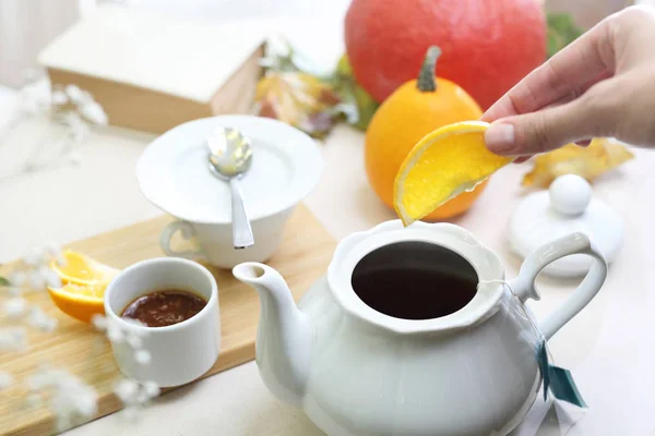 Citrus tea. A woman is brewing aromatic tea in a jug