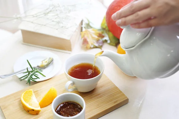 Tea with preserves. A woman pours tea into a cup