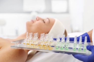 Cosmetics in an ampoule.The beautician holds trays with cosmetic preparations in her hand.  clipart