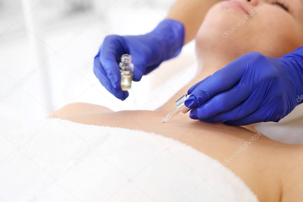 Skin care in a beauty salon.Beautiful smooth neckline and neck, the beautician applies the serum to the woman's body.