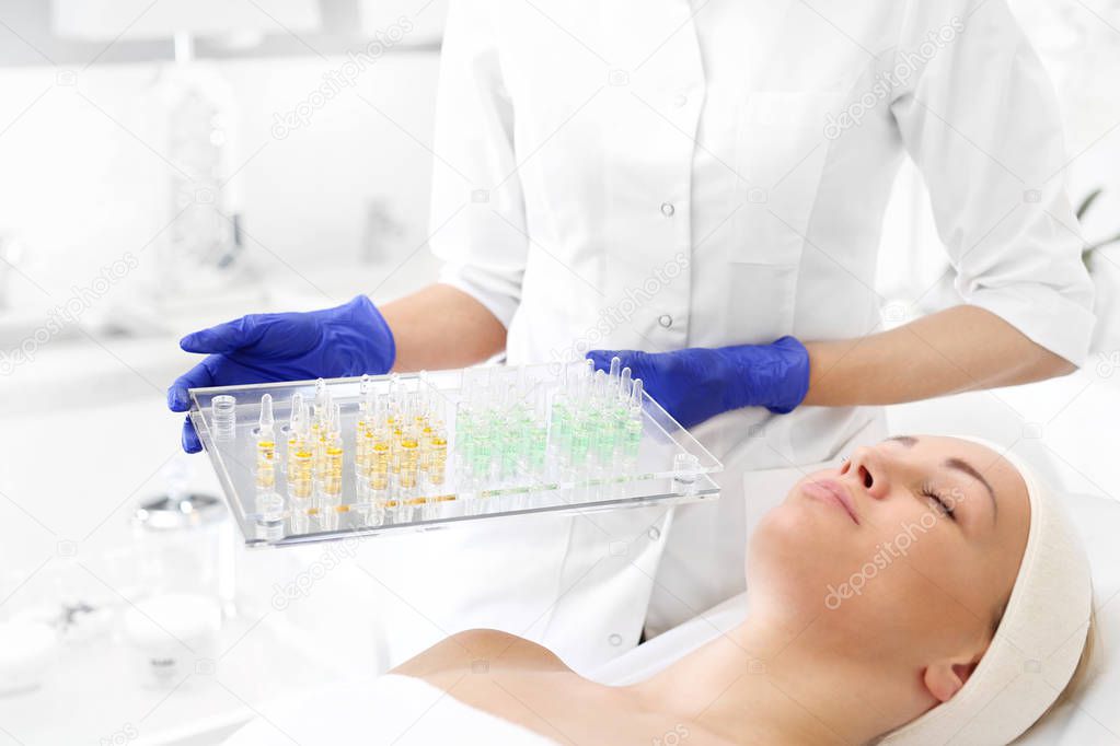 Cosmetic ampoules. The beautician holds trays with cosmetic preparations in her hand. 