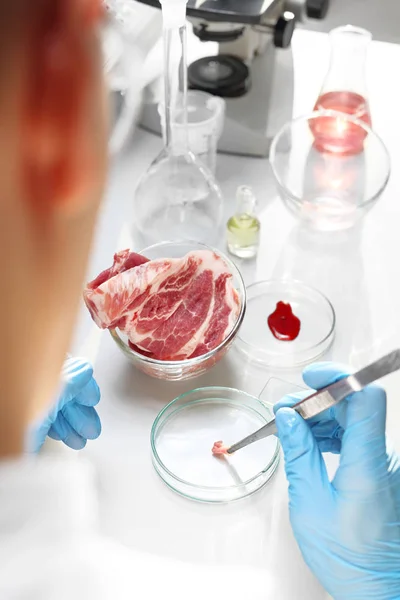 Laboratory meat inspection. The laborer examines the quality of meat in a research laboratory.