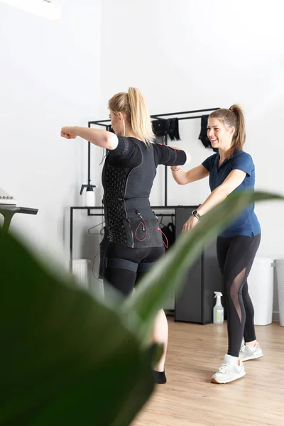 フィットネス クラブでトレーニング 筋肉を刺激するために特別な服装の女性運動 — ストック写真