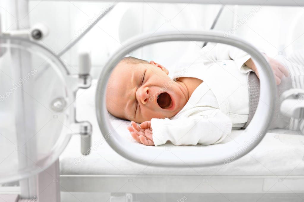 Newborn baby in an incubator.A newborn baby in an incubator in a hospital ward.