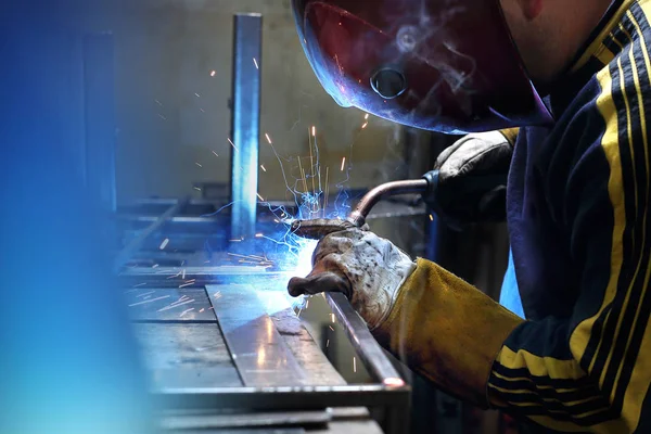 Welding of metal. The man works in the workshop.