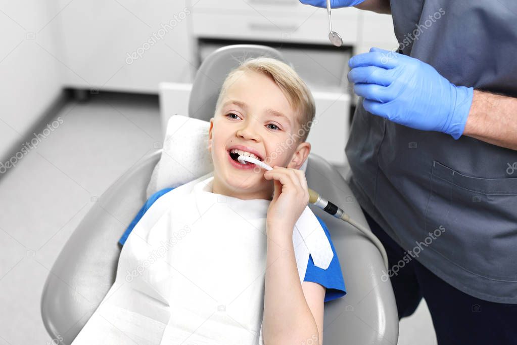 Tooth treatment, the dentist cleans the cavity. A dental office, a child in a dental chair