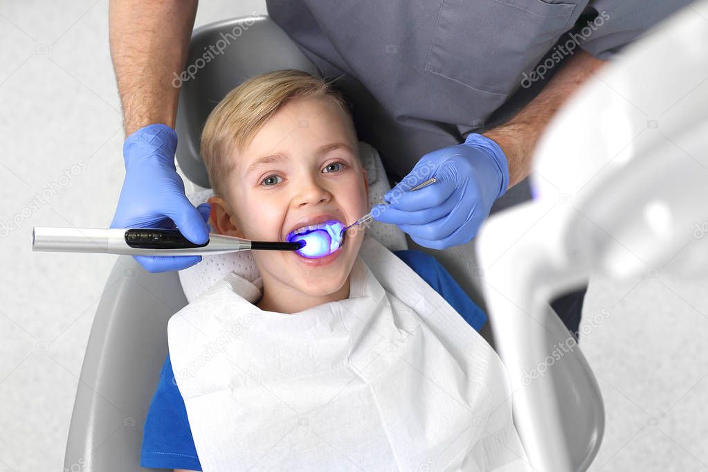 Child at the dentist. Tooth treatment, the dentist cleans the cavity