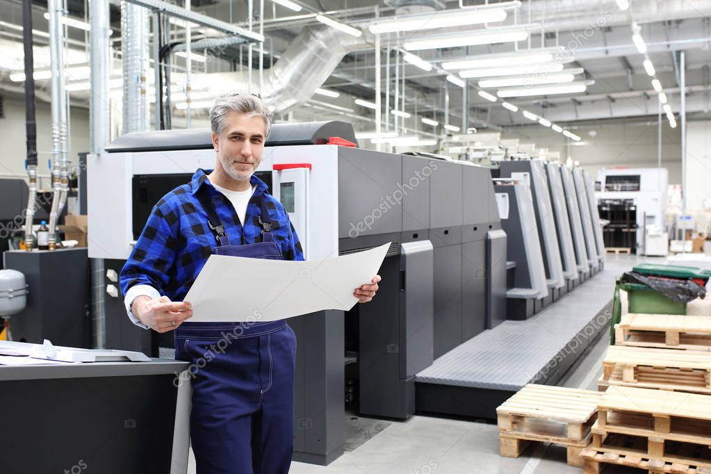 Printer. The man checks the print quality.