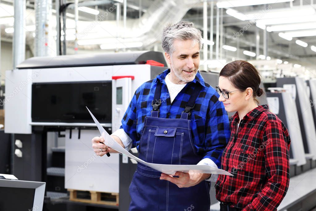 Printing house. A woman and a man are watching the printout