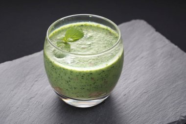 Ispanak, lahana, avokado ve nane yaprağı ile süslenmiş muz yapılan yeşil smoothie.