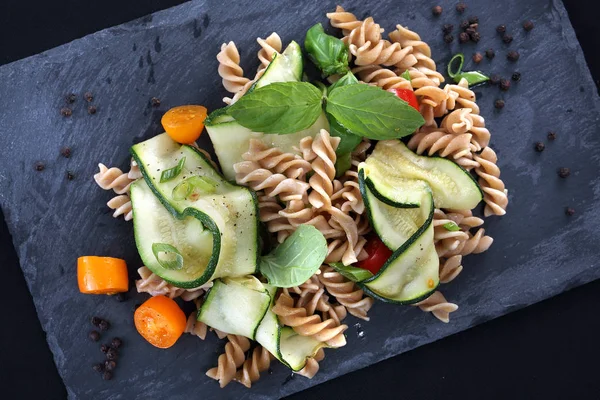 Macaroni salad. Spiral pasta with vegetables. on a black plate. — Stock Photo, Image