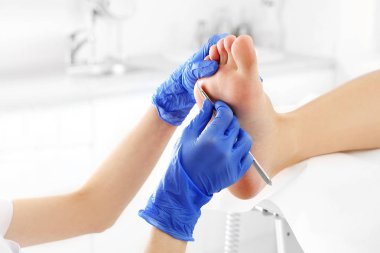 Podiatry. Removing calluses with a scalpel at the beautician. clipart