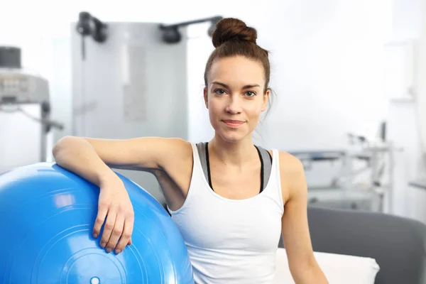 Entrenador de fitness de belleza con una pelota de gimnasio azul después del entrenamiento . — Foto de Stock