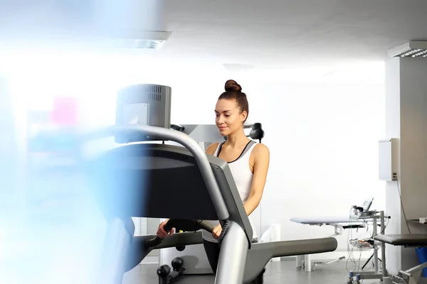 Uma jovem mulher em uma sala de exercícios está correndo em uma esteira automática . — Fotografia de Stock