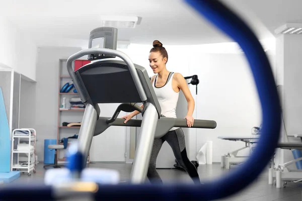 Een jonge vrouw in een sportzaal wordt uitgevoerd op een automatische loopband. — Stockfoto