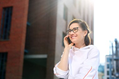 Cep telefonuyla konuşuyorum. Mutlu, gülümseyen genç kadın telefonda konuşuyor.