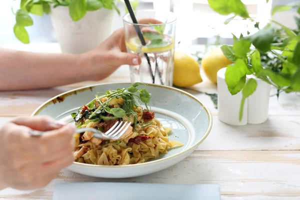 サーモンと日干しトマトのスパゲッティ。女性はおいしい料理を食べる — ストック写真