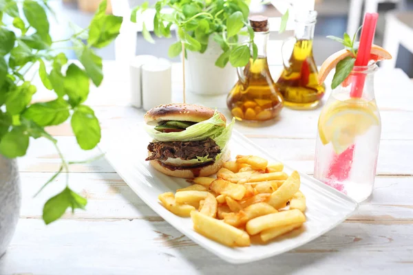 Burger mit Rinderhackfleisch. leckeres Brötchen serviert mit gebratenen Pommes. — Stockfoto