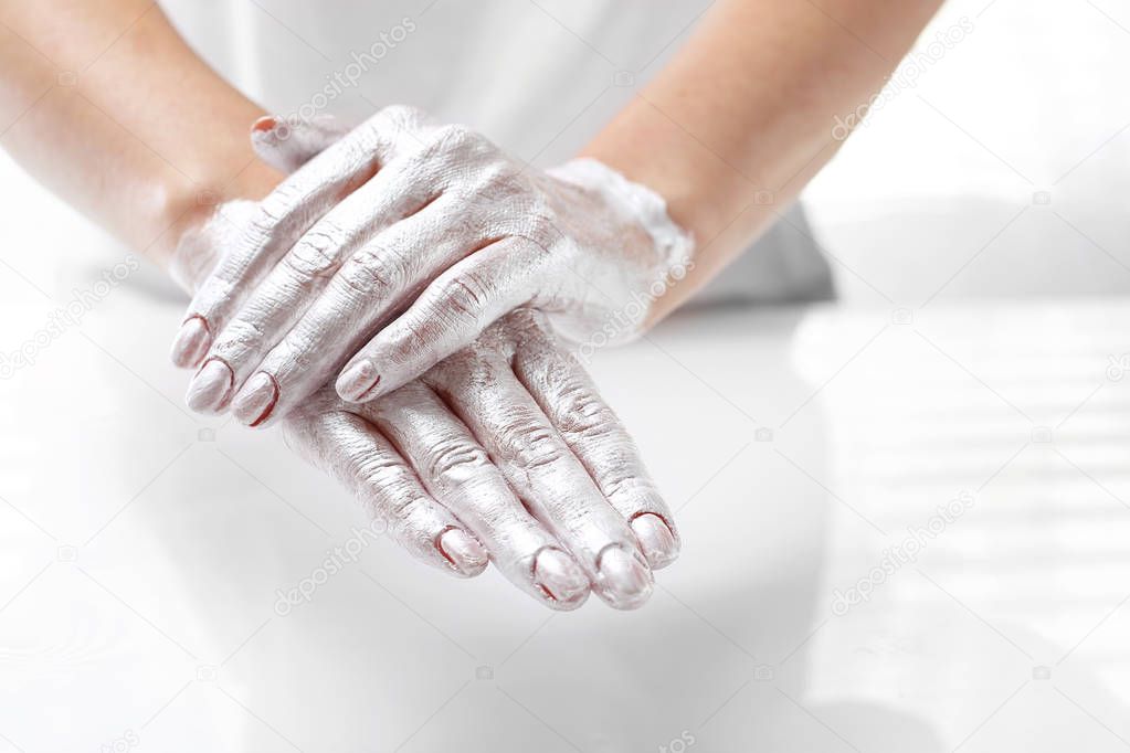 Beautiful and smooth hand skin. The woman puts a mask on the skin of the hand. Hand skin care.