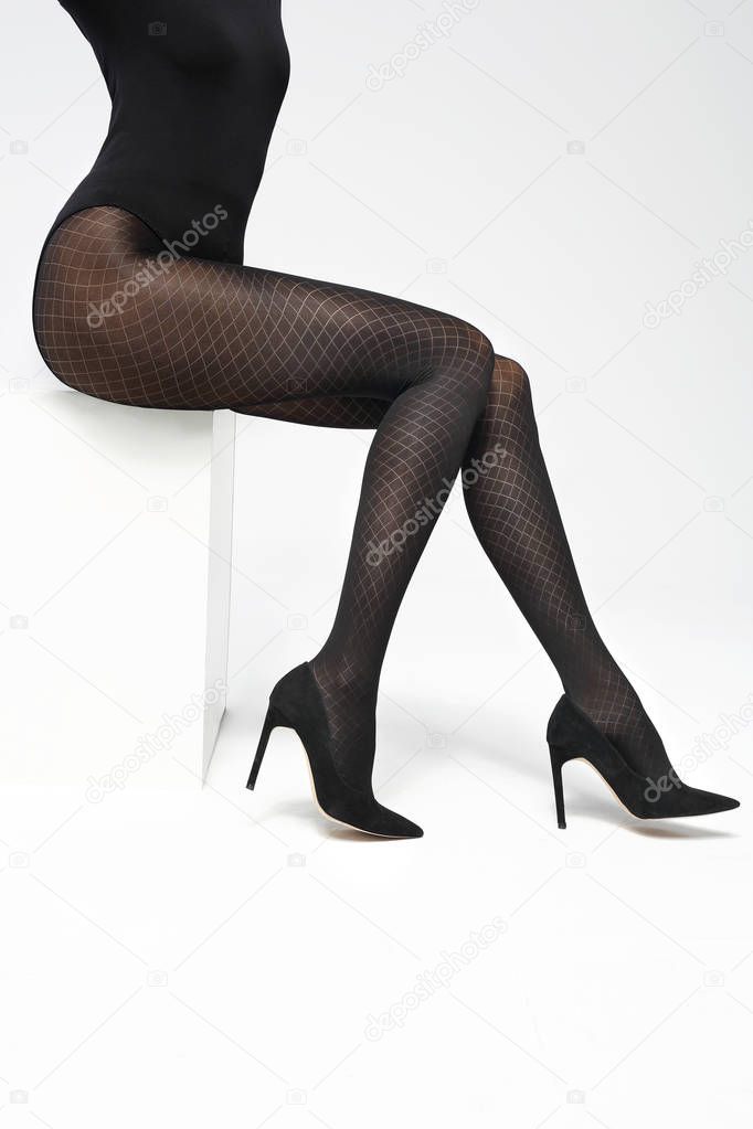 Legs of a young woman in black tights. Female legs in black tights on a white background.