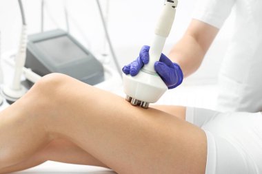 Kalça modelliği ve zayıflatma. Bir kadın radyo dalgalı bir kafa kullanarak zayıflatma prosedüründe.