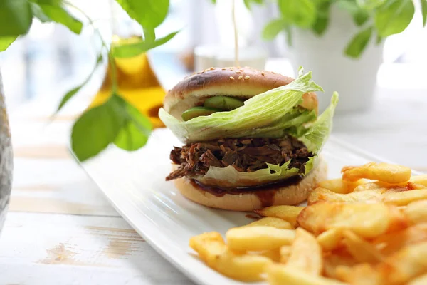 Burger mit Rinderhackfleisch. leckeres Brötchen serviert mit gebratenen Pommes. — Stockfoto