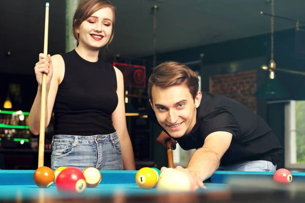 Billiard game. A woman and a man are playing pool in the club