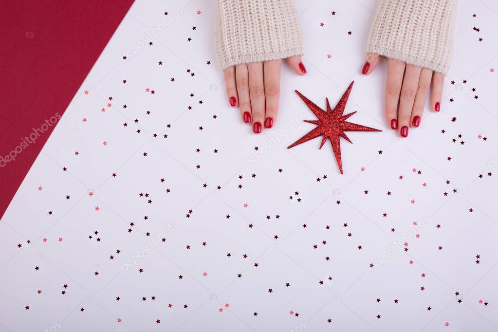 Stylish trendy red festive female manicure. Beautiful young woman's hands on white and red background. Place for text. Flat lay style.