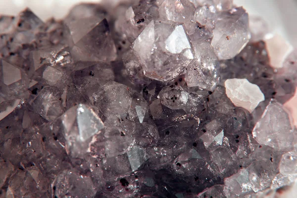 Gemstone Amethyst closeup as a part of cluster geode filled with rock Quartz crystals.