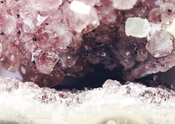 Gemstone Rose Quartz closeup as a part of cluster geode filled with rock crystals.