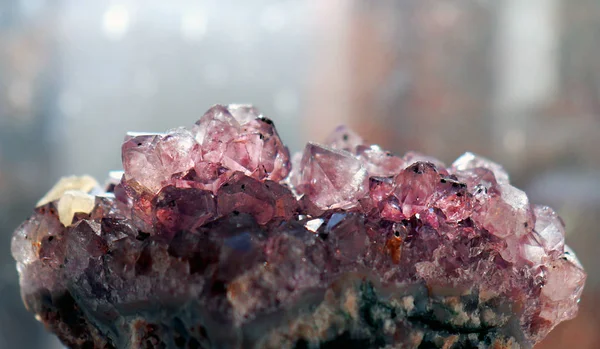 Gemstone Amethyst closeup as a part of cluster geode filled with rock Quartz crystals.