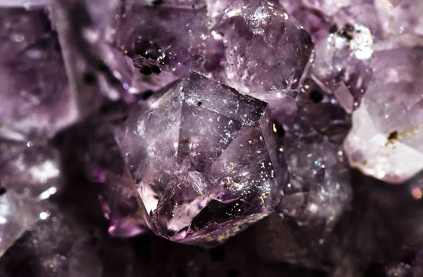 Gemstone Amethyst closeup as a part of cluster geode filled with rock Quartz crystals.