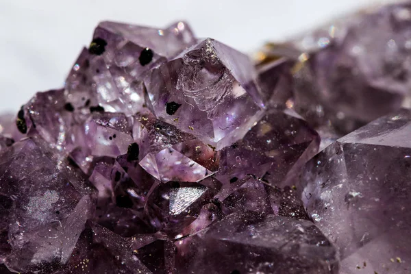 Gemstone Amethyst closeup as a part of cluster geode filled with rock Quartz crystals.