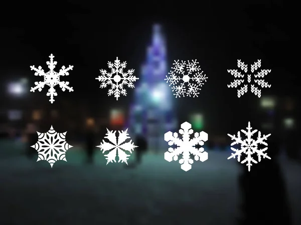 Conjunto de flocos de neve. 8 tipos de flocos de neve. Ícones de flocos de neve em um fundo borrado com uma paisagem noturna de uma árvore de Ano Novo — Vetor de Stock