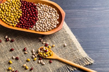 Tahta kaşık ahşap arka plan üzerinde fasulye çeşididir. Mung fasulye, yer fıstığı, Kuru fasulye ve kahverengi fasulye.