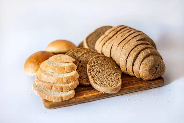 Bread and buns on the kitchen board. Sliced bread. Appetizing bread in the photo. Bread on the table. Fresh bread on a white background. Sliced bread. A loaf of bread. Assortment of bread