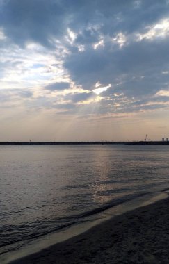 Bir roadline içinde bir ufuk ile göl ve sandy beach üzerinde ağır bulutlar arkasında güneş