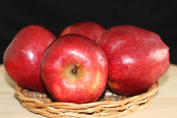 Four red apples on straw plate