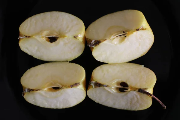Four pieces of apple on black plate