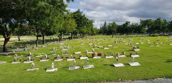 Mezarlık, mezar taşları ve çimenlerde çiçekler