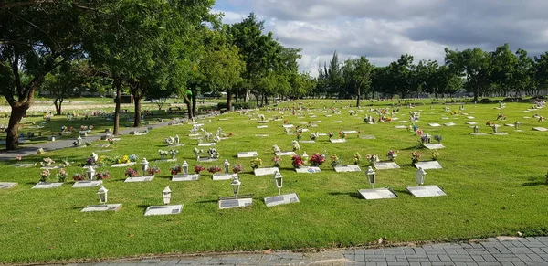 Mezarlık, mezar taşları ve çimenlerde çiçekler