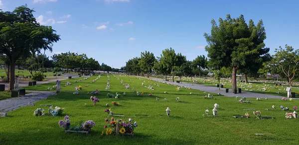 Mezarlık, mezar taşları ve çimenlerde çiçekler