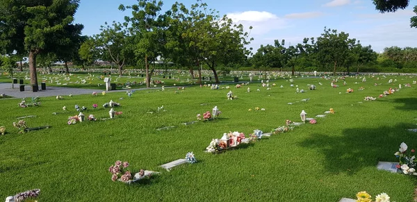 Mezarlık, mezar taşları ve çimenlerde çiçekler