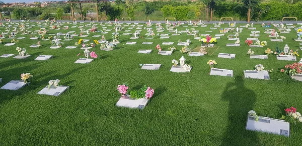 Mezarlık, mezar taşları ve çimenlerde çiçekler