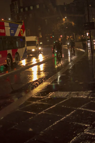 Die beleuchtete Straße mit Beleuchtung und Reflexion mit Fahrrädern und anderem Verkehr — Stockfoto