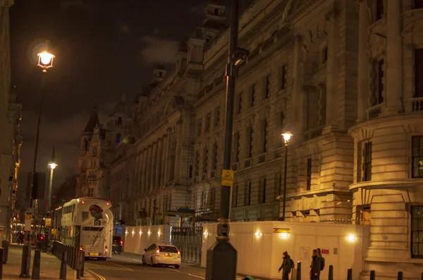 Londense straten in de nacht met straatverlichting die op stenen gebouwen valt — Stockfoto