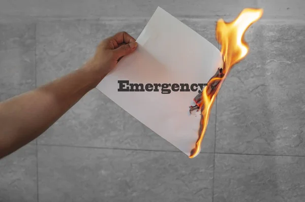 Texto de emergencia con papel quemado en la mano — Foto de Stock