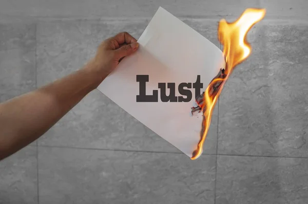 Lujuria texto en el fuego sobre papel quemado — Foto de Stock