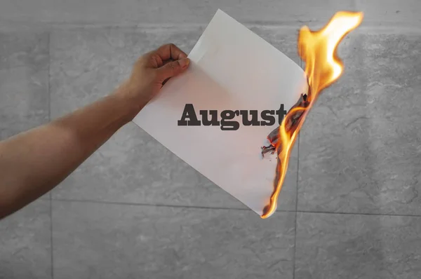 Palabra de agosto texto en llamas con papel quemado — Foto de Stock