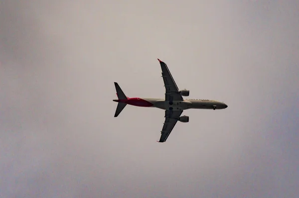 Avión en el cielo con nubes en Londres bajando —  Fotos de Stock